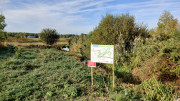 Un panneau d’information présente un plan au milieu d’un paysage verdoyant et au bord d'une rivière